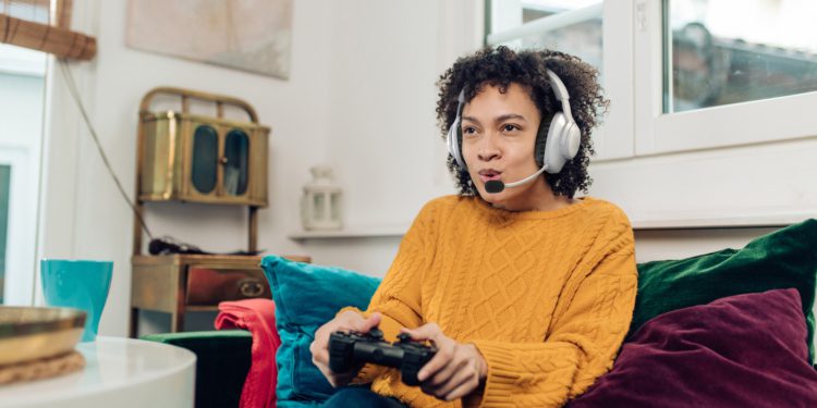 Portrait of a young African American woman playing video games at home and having fun.
